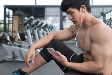 genç adam fitness merkezinde cep telefonu kullanın. erkek atlet liste