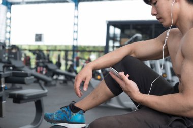 genç adam fitness merkezinde cep telefonu kullanın. erkek atlet liste
