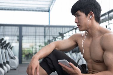 genç adam fitness merkezinde cep telefonu kullanın. erkek atlet liste