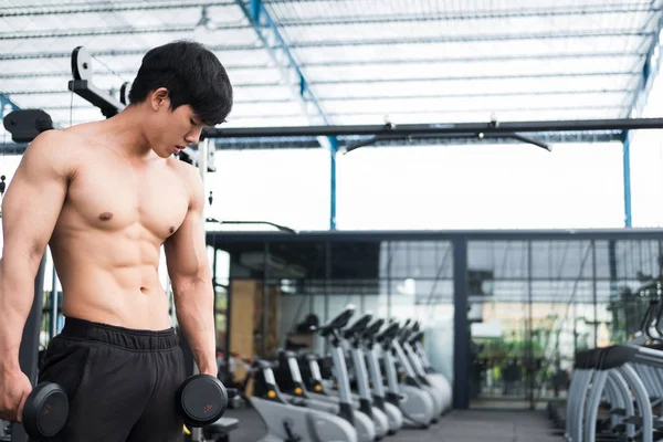 男子举哑铃在健身房。工作在 fitnes 的健美男 — 图库照片