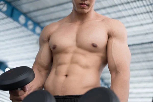 男子举哑铃在健身房。工作在 fitnes 的健美男 — 图库照片