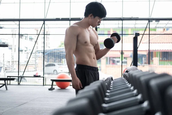 Uomo sollevare manubri in palestra. bodybuilder maschio che lavora in fitnes — Foto Stock