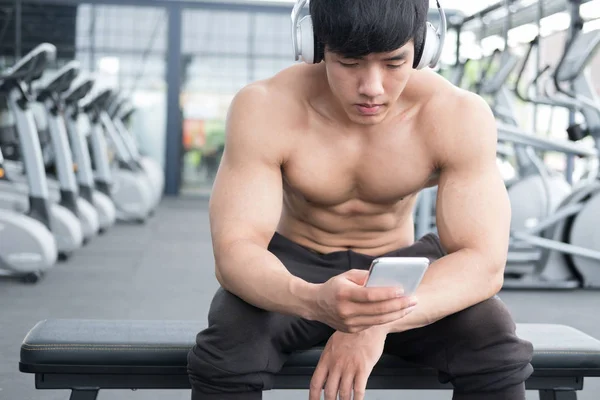 young man use mobile phone in fitness center. male athlete liste
