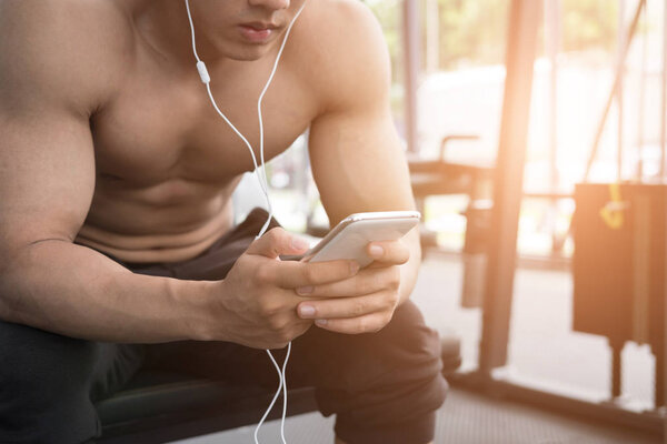 young man use mobile phone in fitness center. male athlete liste