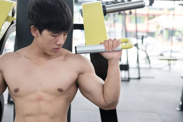 Mladý muž provést cvičení vzpírání stroj ve fitness — Stock fotografie