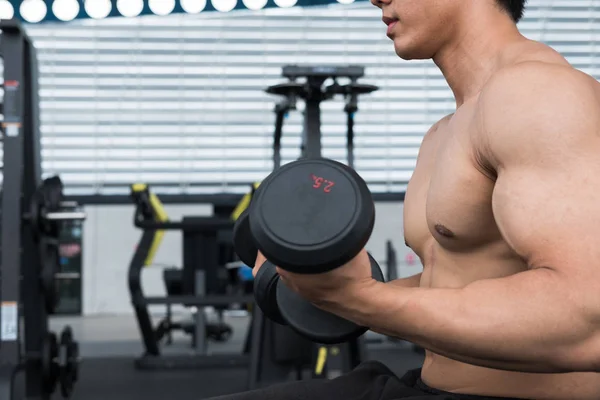 man lift dumbbell in gym. bodybuilder male working out in fitnes