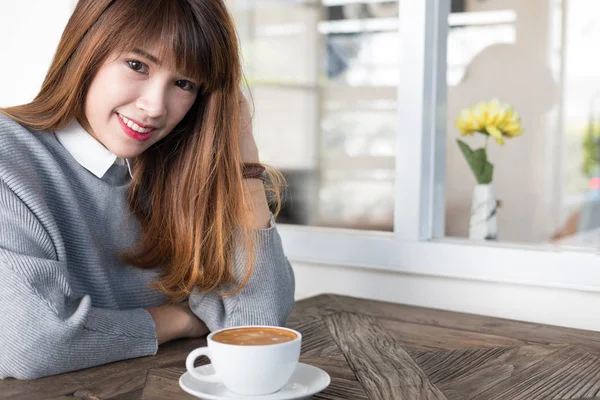 Жінка сидить у кафе з гарячою кавою капучино на дерев'яному столі трилін — стокове фото