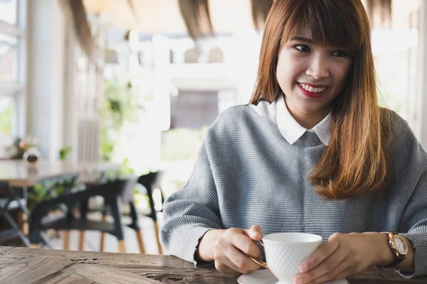 Kadın oturup Cafe ahşap masa Durin'in sıcak cappuccino kahve ile — Stok fotoğraf