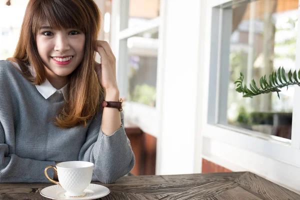 Kadın oturup Cafe ahşap masa Durin'in sıcak cappuccino kahve ile — Stok fotoğraf