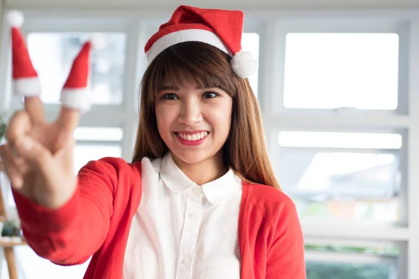 Mulher usar chapéu de Pai Natal mostra dois dedos. ásia feminino desgaste branco — Fotografia de Stock