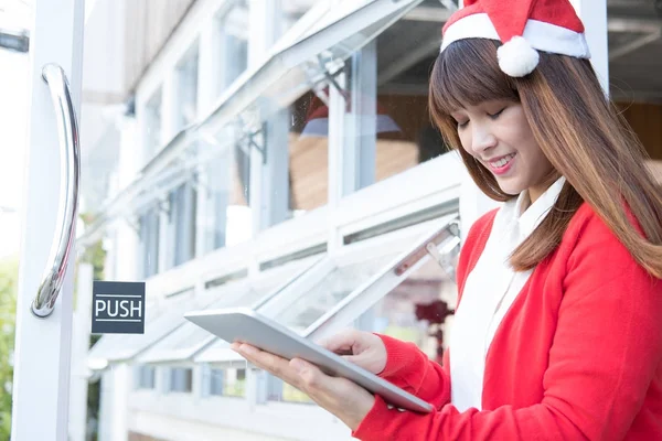 Mulher usar chapéu de Papai Noel segurando tablet em sua loja. asiático feminino nós — Fotografia de Stock