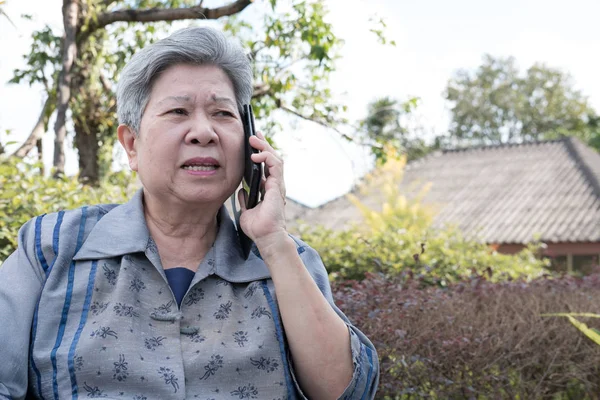 Anciana hablar en el teléfono móvil mientras está sentado en el banco en garde — Foto de Stock