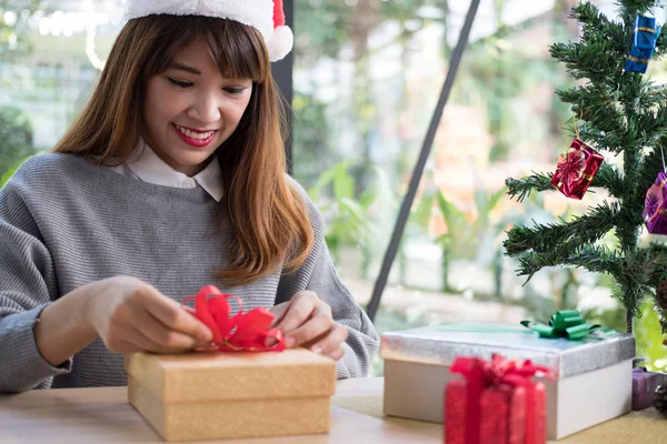 Жінка прикрашає різдвяну подарункову коробку стрічкою. привітання сезону для w — стокове фото