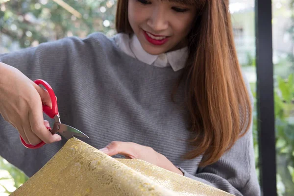 Femme couper du papier cadeau avec des ciseaux pour envelopper boîte cadeau de Noël — Photo
