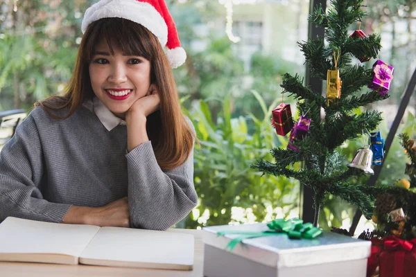 Donna asiatica indossare cappello Babbo Natale a casa. ragazza con taccuino, gi — Foto Stock