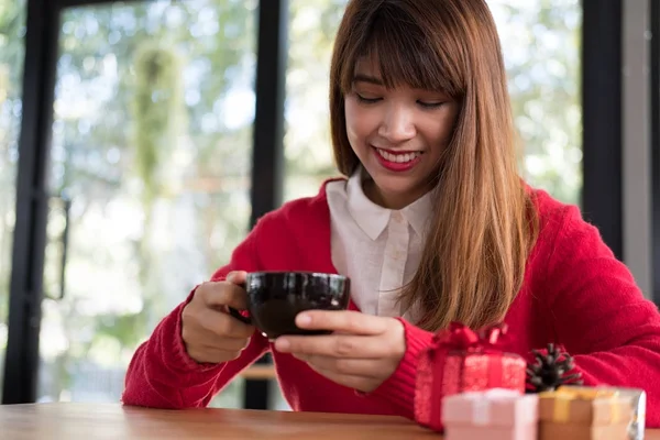 Donna indossa maglione rosso con confezione regalo sul tavolo al ristorante. gir — Foto Stock