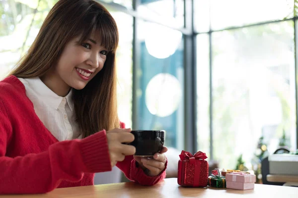 Donna indossa maglione rosso con confezione regalo sul tavolo al ristorante. gir — Foto Stock