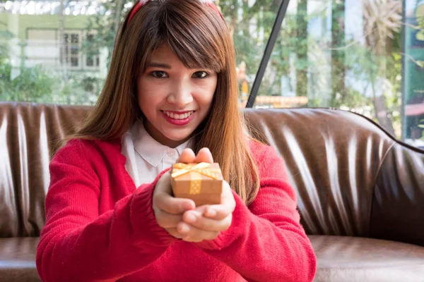 Femme assise près du canapé à la maison. fille avec boîte cadeau. Nom de Dieu — Photo