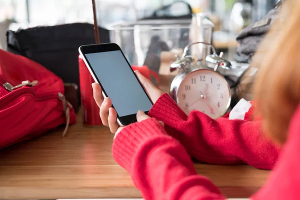 Женщина в красном свитере, использующая смартфон для социальных сетей — стоковое фото