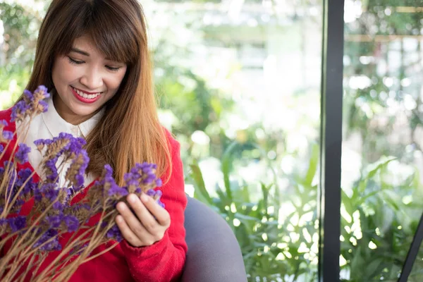 Жінка посміхається, тримаючи букет фіолетової квітки . — стокове фото