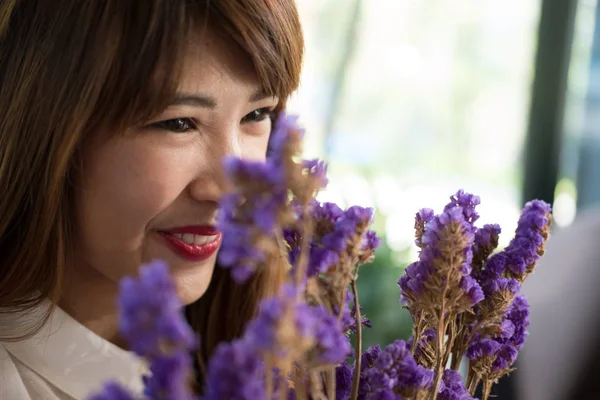 Mulher sorrindo enquanto segurando buquê de flor roxa . — Fotografia de Stock