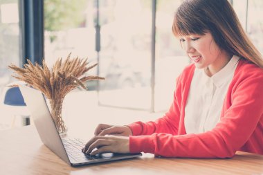 evde bilgisayarda yazarak kırmızı hırka giyen kadın başlatmak. 