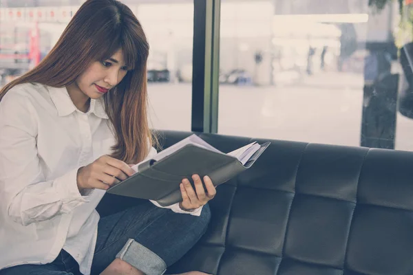 Жінка сидить на дивані в кафе. жіночий студент читає записку в блокноті — стокове фото