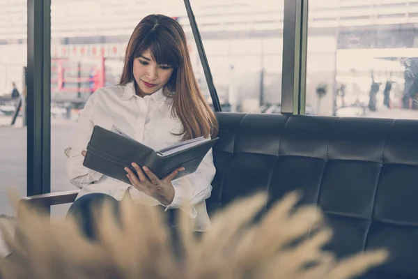 Жінка сидить на дивані в кафе. жіночий студент читає записку в блокноті — стокове фото