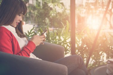 Sosyal networkin için Smartphone kullanarak kırmızı hırka giyen kadın