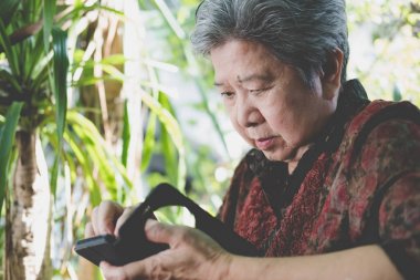 bahçede cep telefonu tutan yaşlı kadın. yaşlı kadın texti