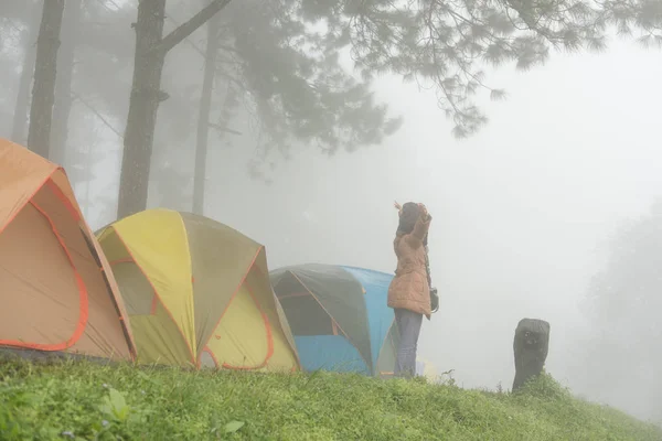 Турист поднимает руку со счастьем возле палатки в тумане и тумане. campi — стоковое фото
