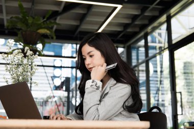 bir kredi kartı tutan ve dizüstü bilgisayar için online kullanan kadın