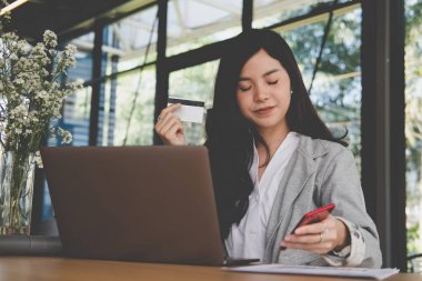 bir kredi kartı tutan ve akıllı telefon için online sho kullanarak kadın