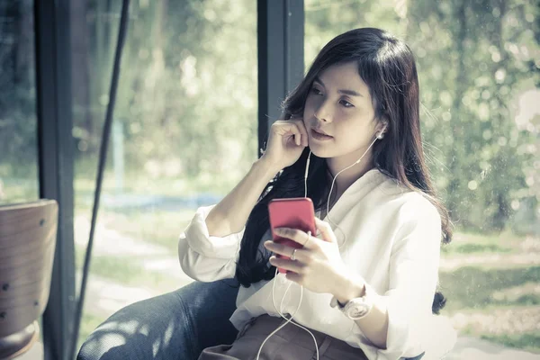 Жінка тримає смартфон і слухає музику з навушниками — стокове фото