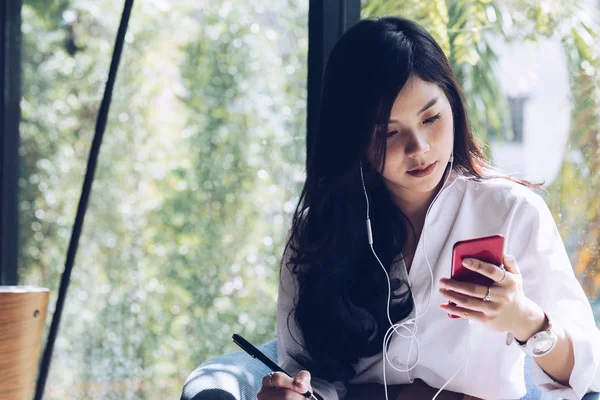 Жінка тримає смартфон і слухає музику з навушниками — стокове фото