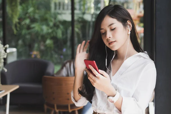 Женщина держит смартфон и слушает музыку с наушниками — стоковое фото