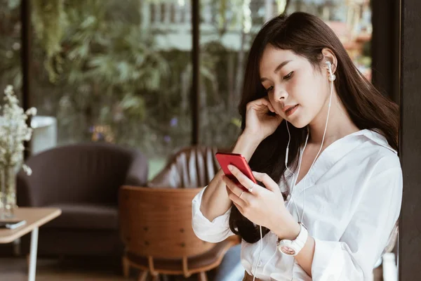 Frau hält Smartphone in der Hand und hört Musik über Kopfhörer — Stockfoto