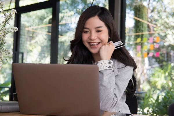 持有信用卡并使用笔记本电脑上网的妇女 — 图库照片