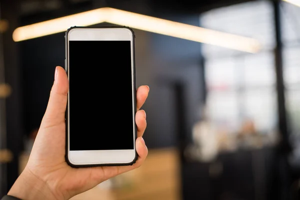 Mockup image of hand holding smartphone in cafe restaurant. mobi — Stock Photo, Image