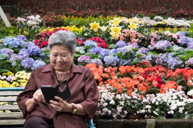 bahçede cep telefonu tutan yaşlı kadın. yaşlı kadın texti