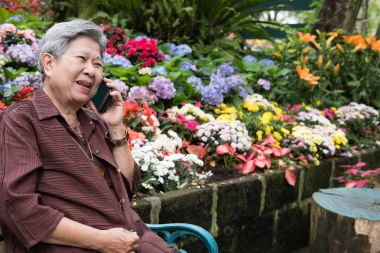hareket eden telefon bahçe içinde yaşlı kadın konuşma. yaşlı kadın konuşmak