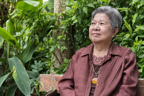 Una anciana descansando en el jardín. anciana mujer relajándose en parque . — Foto de Stock