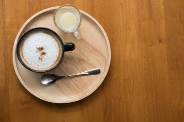 sıcak cappuccino kahve ile ahşap üzerine siyah Kupası'nda toz tarçın 