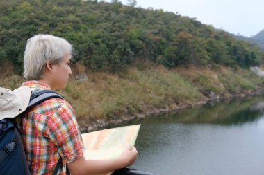 Gezgin adam harita ile orman ve göl summe seyahat sırt çantası