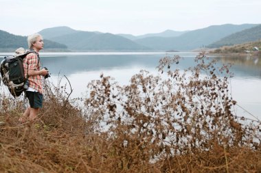 Gezgin uzun yürüyüşe çıkan kimse adam göl kenarında hiking sırt çantası. Turizm backp