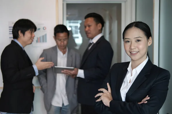 亚洲女商人在镜头前微笑, 而同事们见面 — 图库照片