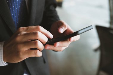 Smartphone holding ve uygulama adam manifatura mesaj kullanarak iş adamı 