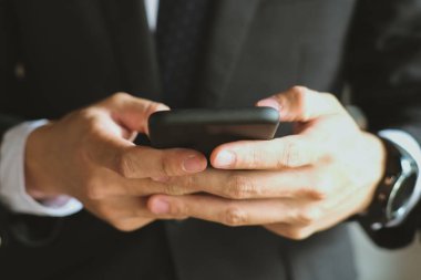 Smartphone holding ve uygulama adam manifatura mesaj kullanarak iş adamı 