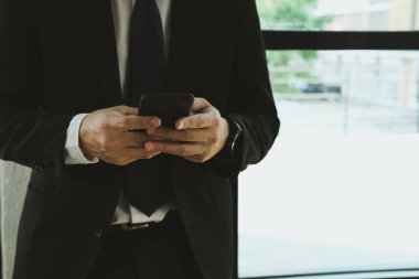 Ofiste akıllı telefon kullanan bir iş adamı. erkek metni