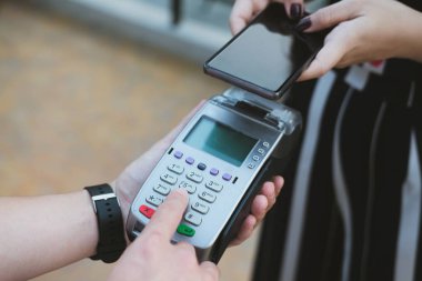 Kadın elektronik okuma ile mobil ödeme yapmak için akıllı telefon kullanıyor